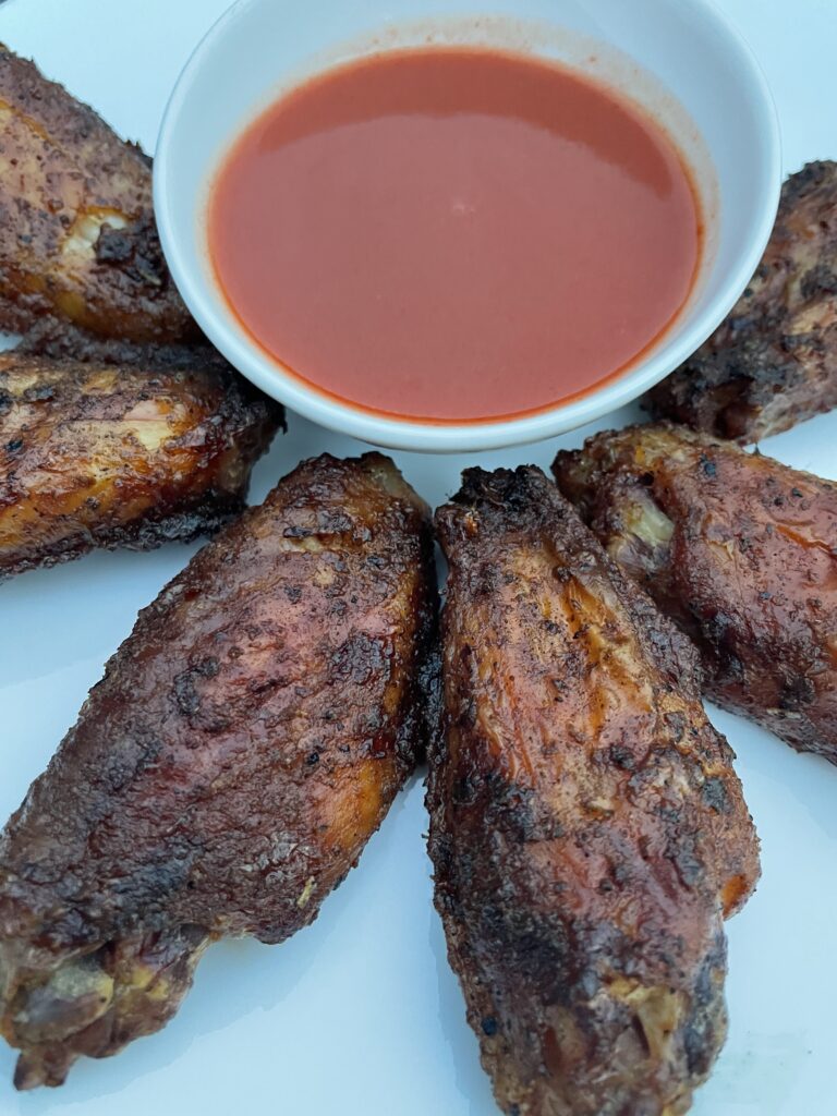 Smoked chicken wings on a plate with hot sauce